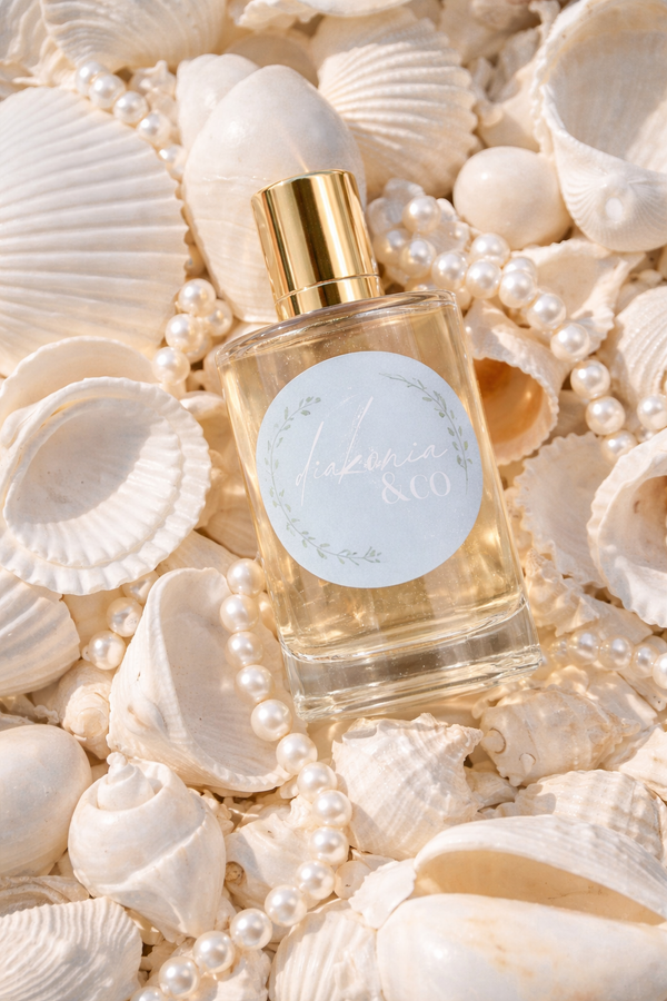 Perfume bottle with a gold cap on a background of seashells and pearls