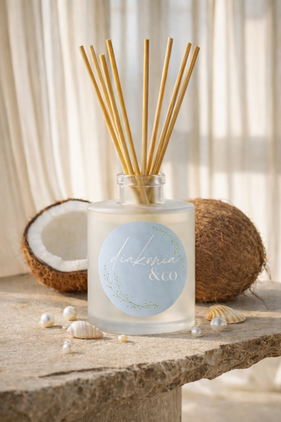 Reed diffuser with wooden sticks on a stone surface with coconuts and pearls