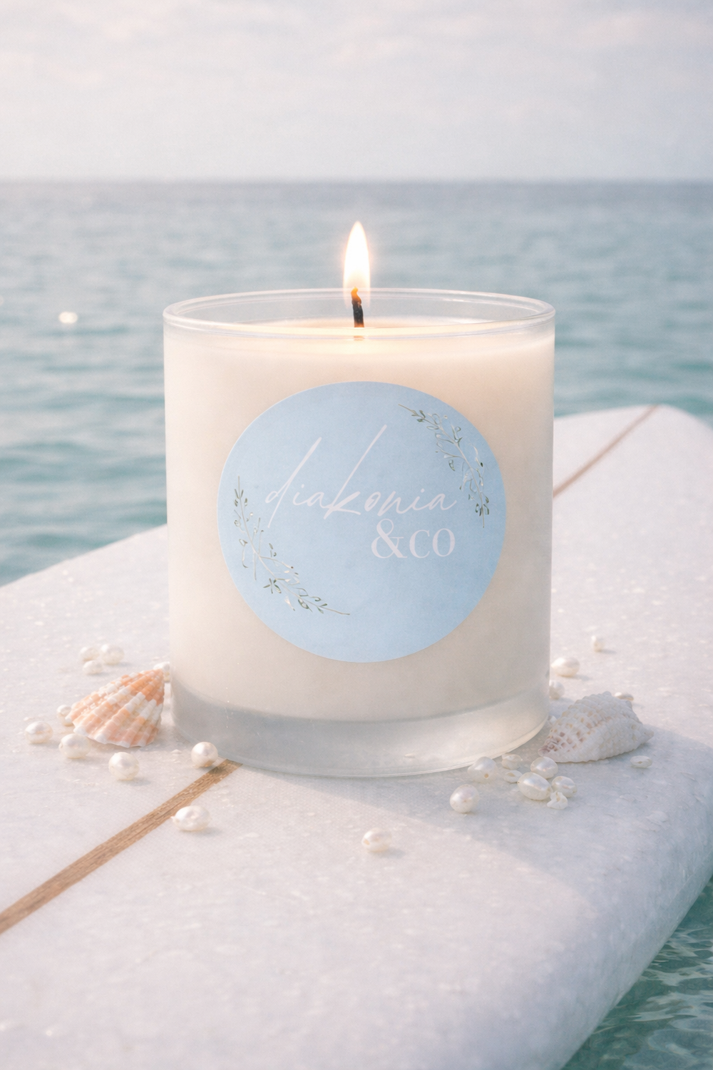 Candle with a blue label on a white surface near water