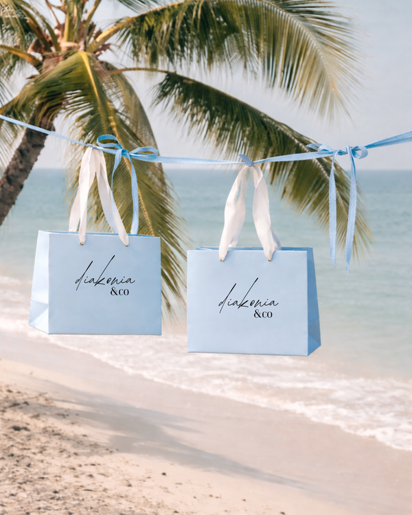 Two bags hanging on a string with palm trees and beach in the background